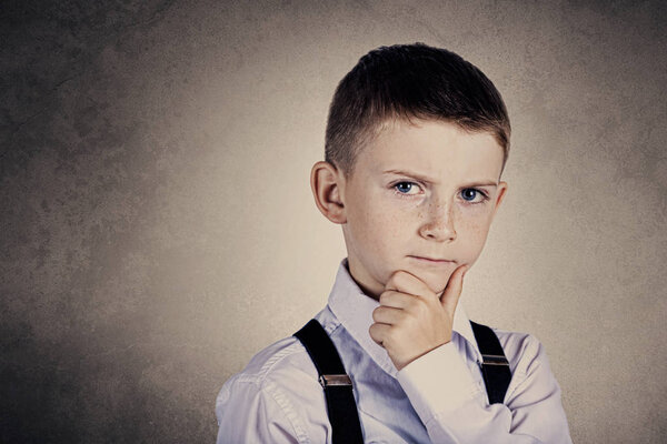 Портрет маленького мальчика, глубоко думающего о чем-то с рукой на подбородке

