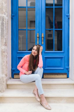 Mavi kapı önünde oturan öğrenci kız