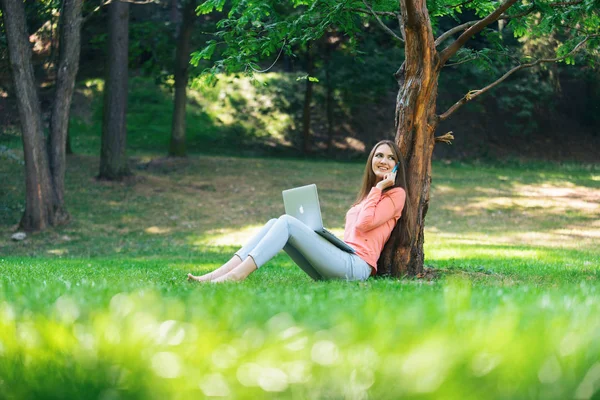 Yeşil bir parkta dizüstü bilgisayarla çalışan öğrenci kız.
