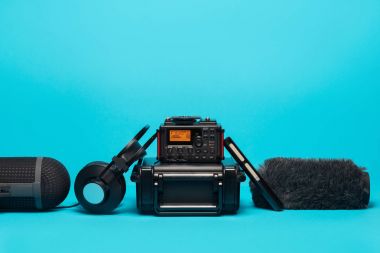 mavi arka plan üzerinde kayıt alan ses donatımı. shotgun mikrofon, kaydedici, ön cam, kulaklık ve servis talebi.