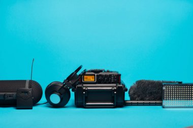 mavi arka plan üzerinde kayıt alan ses donatımı. Ön cam, shotgun mikrofon, radyo sistemi, yazmak, boompole, taşınabilir durumda ve kulaklıklar