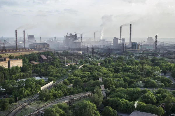 Industrial landscape in Ukraine. Steel factory with smog at sunset. Pipes with smoke. Metallurgical plant. steelworks, iron works. Heavy industry. Ecology problems, atmospheric pollutants.