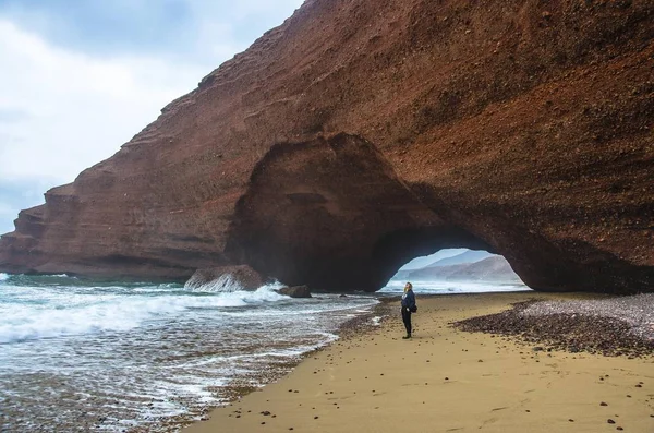 Donna in piedi sulla roccia. Spiaggia di Legzira, Marocco . — Foto Stock