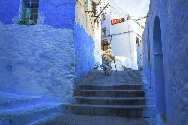 Mujer vestida de típico marroquí, caminando por una calle de la ciudad de Chefchaouen . — Foto de Stock