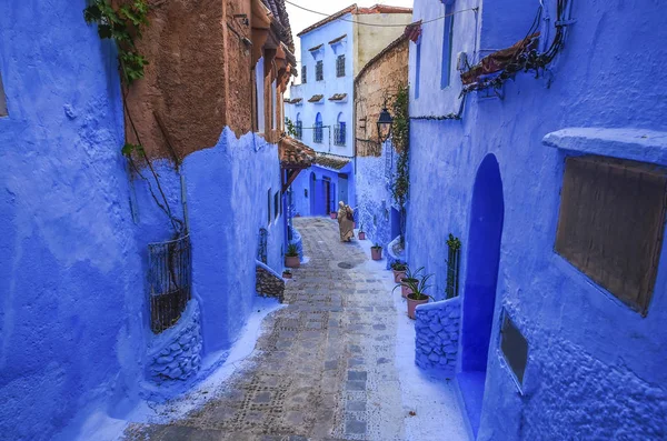 Mujer vestida de típico marroquí, caminando por una calle de la ciudad de Chefchaouen . — Foto de Stock