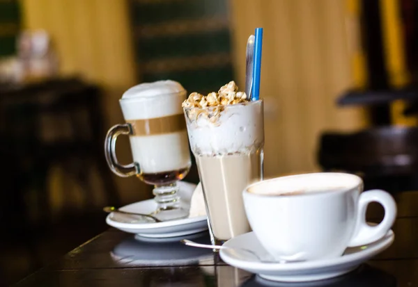 Три различных чашки кофе и на фоне дарк кофе. Капучино, латте и фраппе на столе — стоковое фото