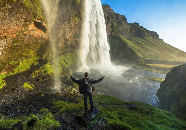 Turist står framför Seljalandsfoss ett av de mest kända vattenfallen på södra Island, Seljalandsfoss, Island — Stockfoto