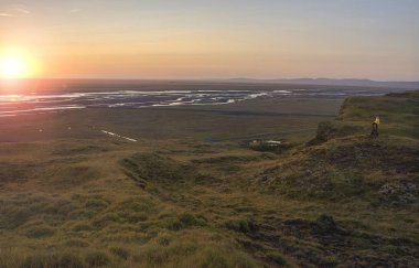 Bir dağ kenarında duran, Seljalandsfoss, İzlanda Nehri Vadisi üzerinde güneşin tadını turist. Mercek parlaması ile.