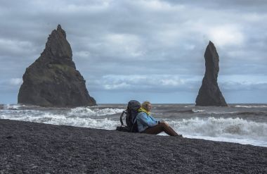 Sırt çantası seatting siyah kum plaj, Vik İzlanda ile turizm