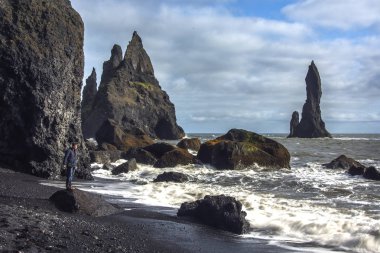 Turist seatting siyah kum plaj - İzlanda
