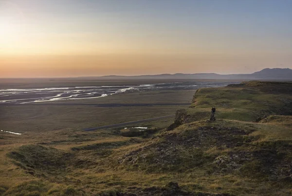 Bir dağ kenarında duran, Seljalandsfoss, İzlanda Nehri Vadisi üzerinde güneşin tadını turist. Mercek parlaması ile.