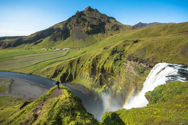 Turista de pie cerca de la hermosa y famosa cascada Skogafoss. Sur de Islandia — Foto de Stock