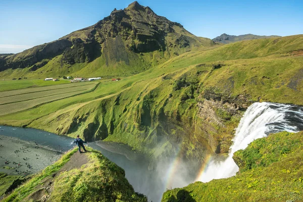 Turista de pie cerca de la hermosa y famosa cascada Skogafoss. Sur de Islandia — Foto de Stock