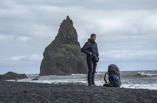 Turista con mochila de pie en la playa de arena negra, Vik en Islandia — Foto de Stock