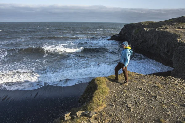 Chica en ropa cálida de pie en el acantilado en el fondo de las montañas en Islandia. Viaje a Islandia — Foto de Stock