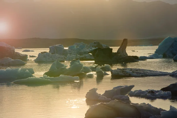 Παγόβουνα στο κρυσταλλικό Λιμνοθάλασσα Γιόκουλσάρλον κατά τη διάρκεια ένα ζωντανό κόκκινο ηλιοβασίλεμα — Φωτογραφία Αρχείου