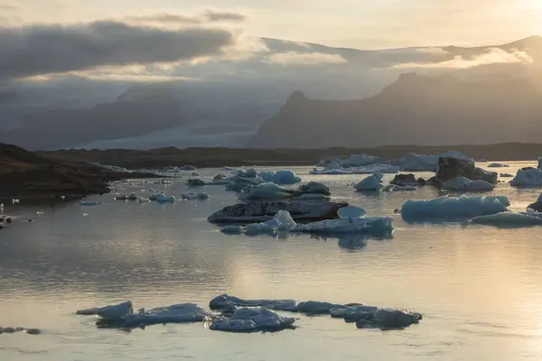 Icebergs em Jokulsarlon lagoa glacial durante um pôr-do-sol vermelho vibrante — Fotografia de Stock