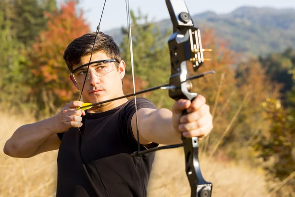 Archer drawing his compound bow trees — Stock Photo, Image