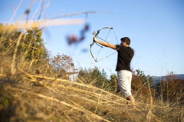 Archer drawing his compound bow trees — Stock Photo, Image