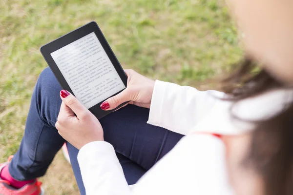 Attractive young woman with e-book/tablet in the park — Stock Photo, Image