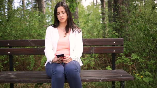 Aantrekkelijke jonge lachende vrouw met smartphone in het park. Schuif de schuifregelaar — Stockvideo