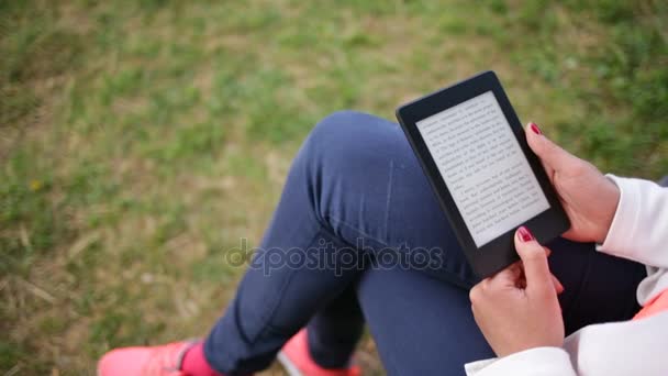 Atractiva joven con libro electrónico / tableta en el parque. Deslizador de diapositivas — Vídeo de stock