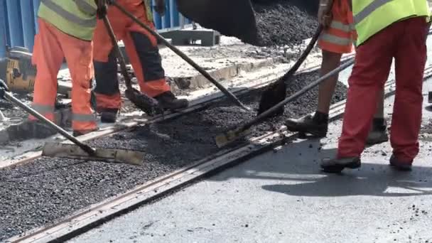Рабочие строят асфальтовую дорогу и железные дороги — стоковое видео