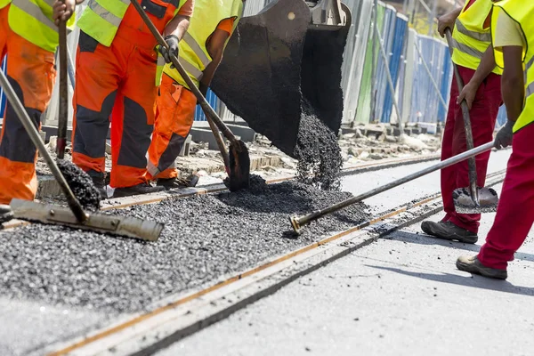 Arbetare konstruera asfalterad väg och järnväg fodrar — Stockfoto
