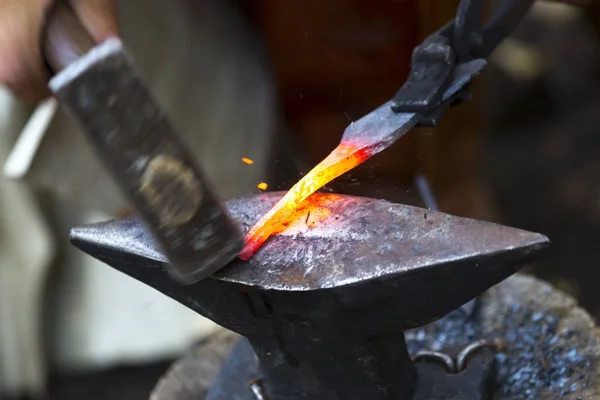 Кузнец бьет по горячей металлической стреле — стоковое фото