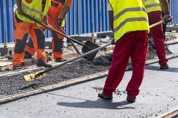 Arbetare konstruera asfalterad väg och järnväg fodrar — Stockfoto