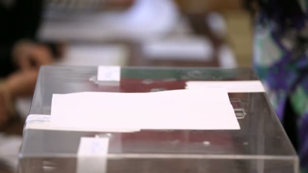 一个女人把她的信封票扔进了一个透明的塑料投票箱 人的手投票 — 图库视频影像