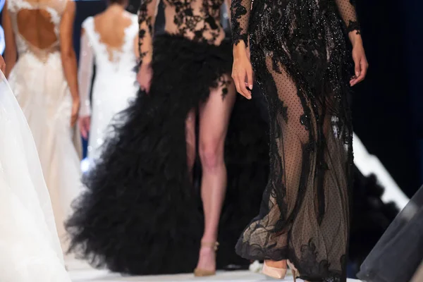 女性モデルは ファッションショー中に美しいデザイナーのドレスで滑走路を歩く 新しいコレクションの服を示すファッションキャットウォークイベント 誰も知らない黒のドレス脚だけ — ストック写真