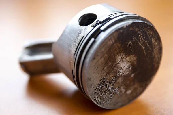 Broken piston rod with injured surface is seen in a wooden table.