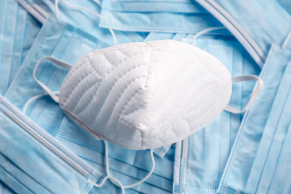 蓝色外科口罩上的白色防护口罩 科罗纳韦勒斯 Covid 歇斯底里症导致了2020年初的大规模口罩短缺 免版税图库图片