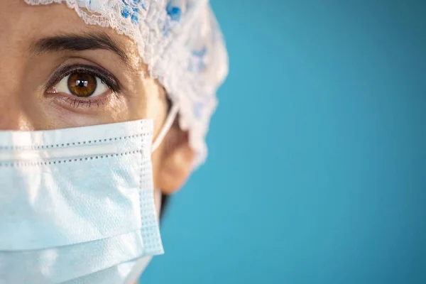 在Covid 19爆发流行病期间 有蓝色防护帽和外科口罩的护士 近景肖像画与单一使用蓝色保护面具在脸上 Studio 图库图片