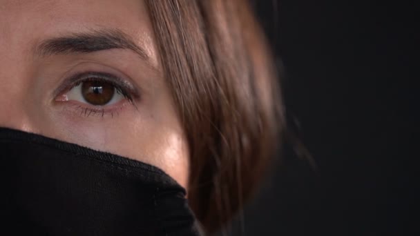 科罗纳韦勒斯病 Covid 爆发期间 年轻女性戴着黑色防护面罩 在黑色背景上贴上带有多用途保护面具的摄影棚肖像 — 图库视频影像