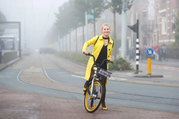 Junge Frau mit Fahrrad in einer nebligen Stadt — Stockfoto