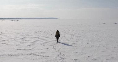 Kadın kışın donmuş körfezde yürüyor