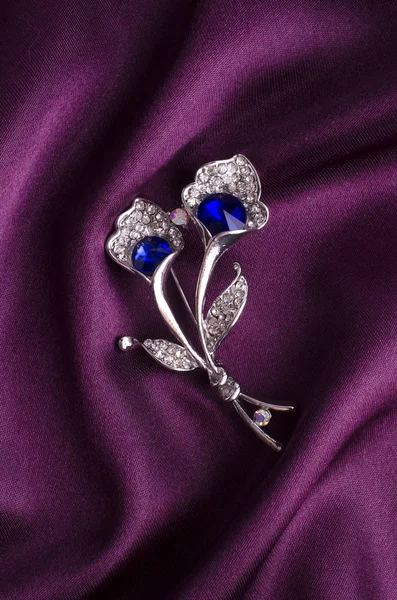 Zilveren broche bloem met blauwe steen op zijde — Stockfoto
