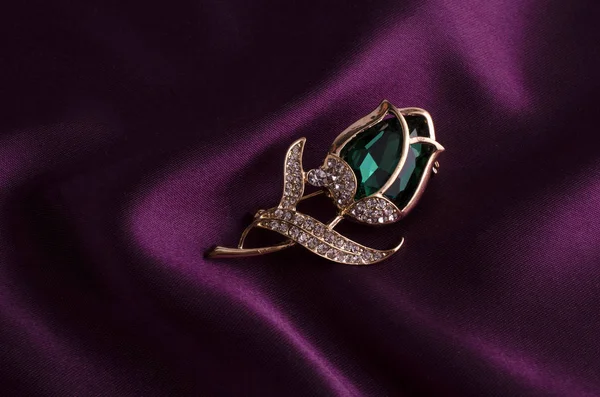 Gold brooch rose bud with emerald and diamonds on silk — Stock Photo, Image