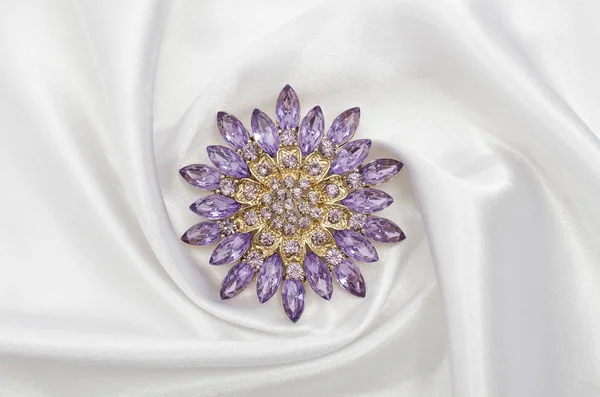 Rund lila brosch med diamanter på sidentyg — Stockfoto