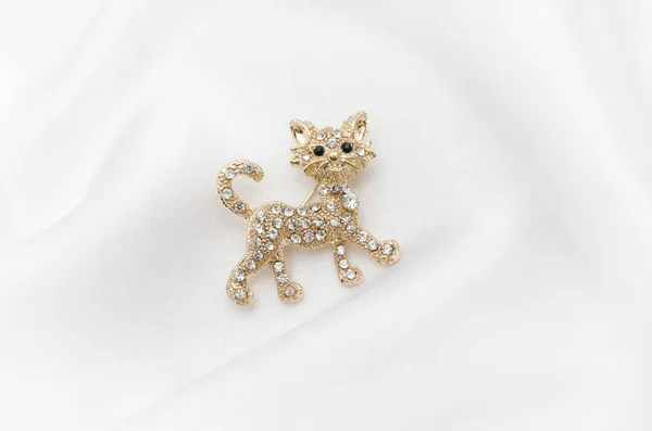 Brooch golden kitten with diamonds on silk fabric — Stock Photo, Image