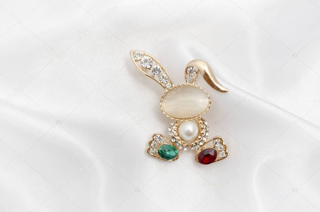 Golden brooch bunny with diamonds and moonstone on silk fabric