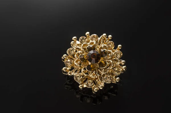 gold round brooch with diamonds isolated on black