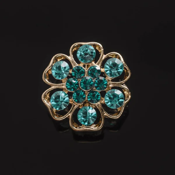 Zlaté kolo brož s modré diamanty izolované na černém pozadí — Stock fotografie