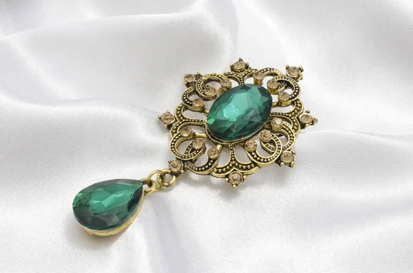 Broche vintage dorado con esmeraldas sobre seda —  Fotos de Stock