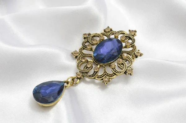 golden vintage brooch with blue stone on silk