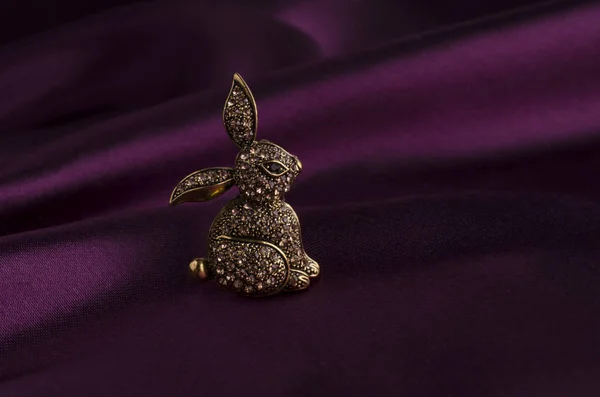 Золотая брошь кролика с бриллиантами на шелке — стоковое фото