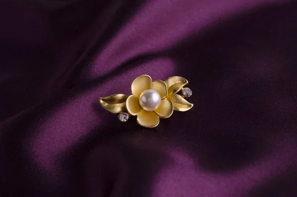 Gold brooch flower with pearl on silk — Stock Photo, Image