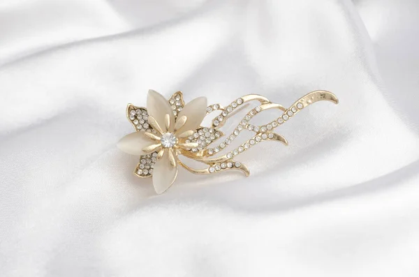 Broche de oro flor con gemas y piedra lunar sobre seda —  Fotos de Stock